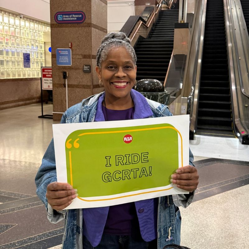 Woman holding a sign that reads "I RIDE GCRTA!"